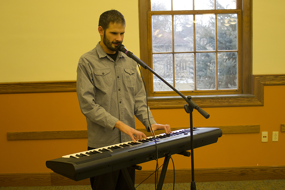 A man plays a keyboard and sings into a microphone.